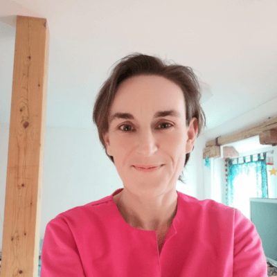 Man sieht den Oberkörper von Jeannine Gashi. Der Hintergrund ist weiss. Jeannine trägt ein pinkes Oberteil.