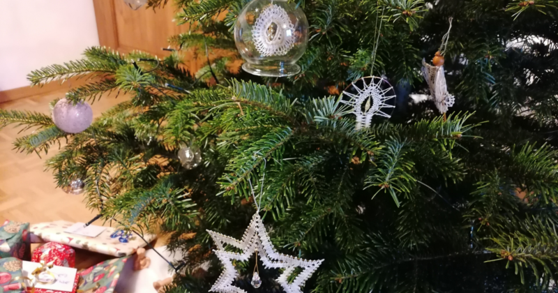 Man sieht geklöppelten Baumschmuck auf einem Weihnachtsbaum.